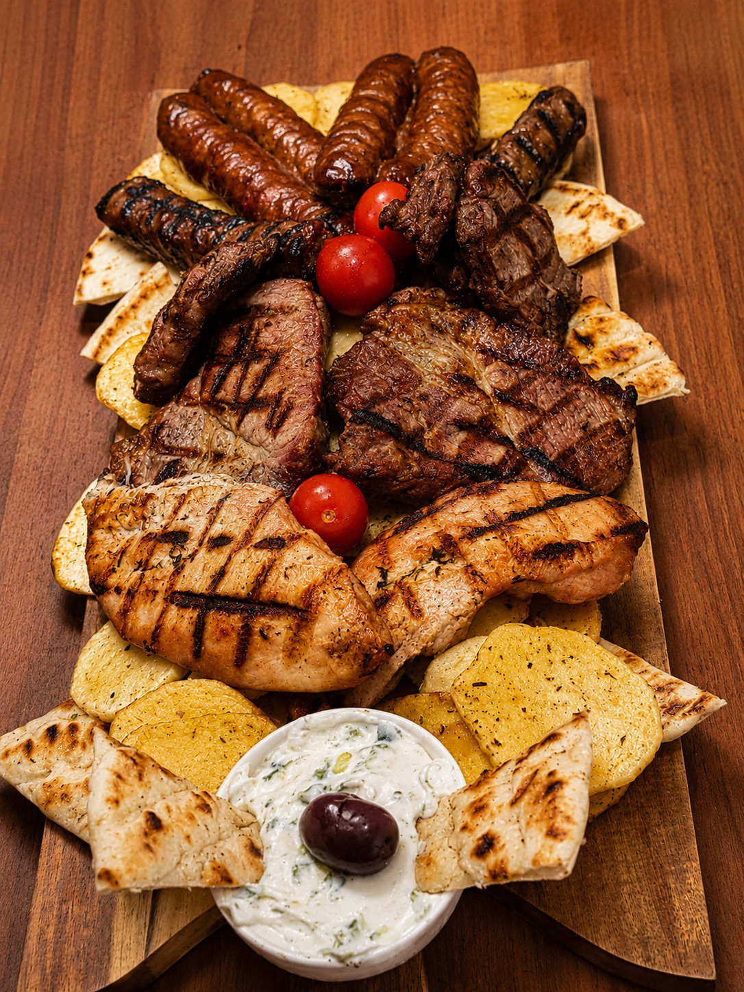 A Greek mixed grill board with pitta, potatoes and tzatziki