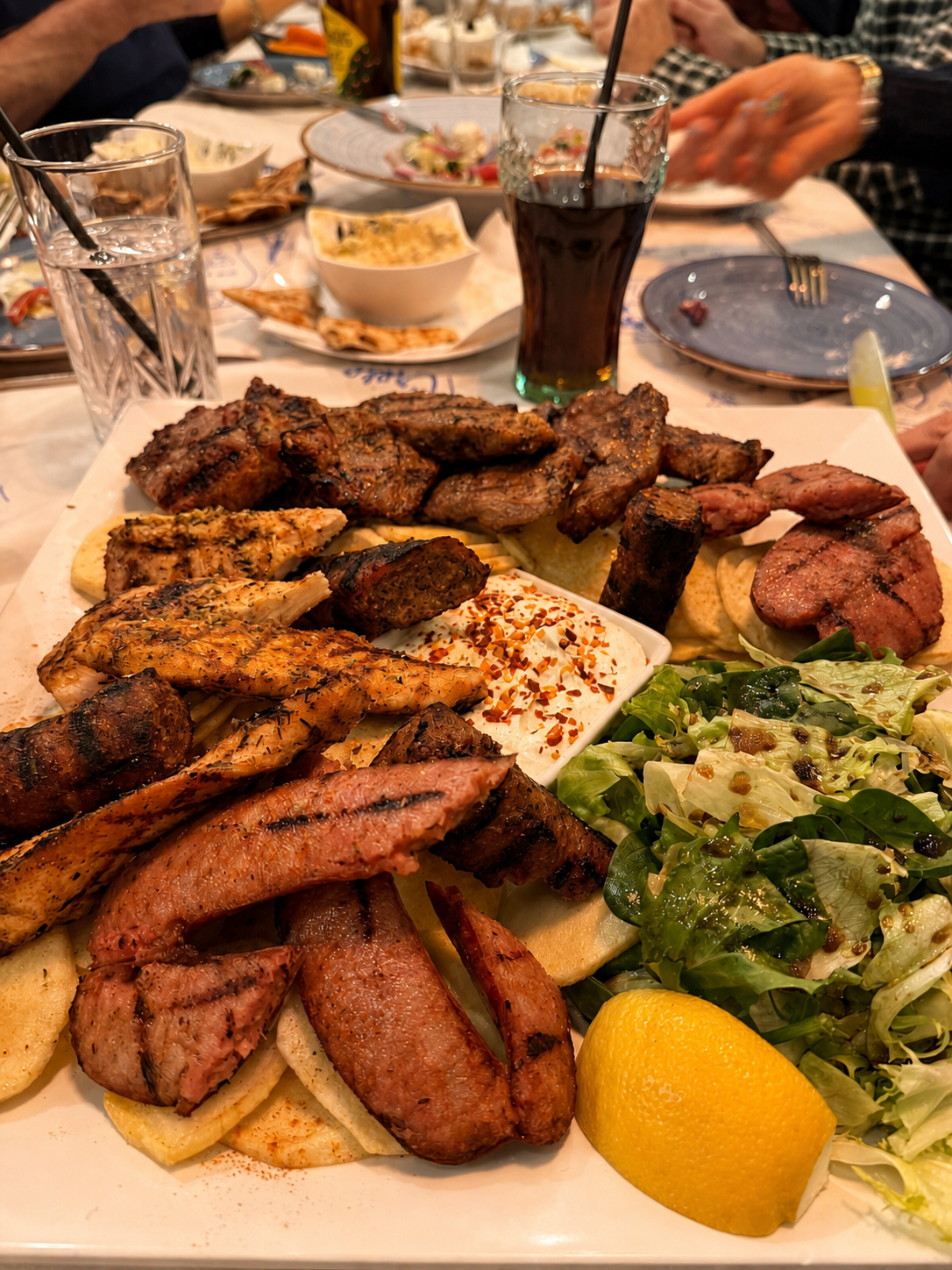 A mixed grilled meat sharing platter with pitta, salad and dip